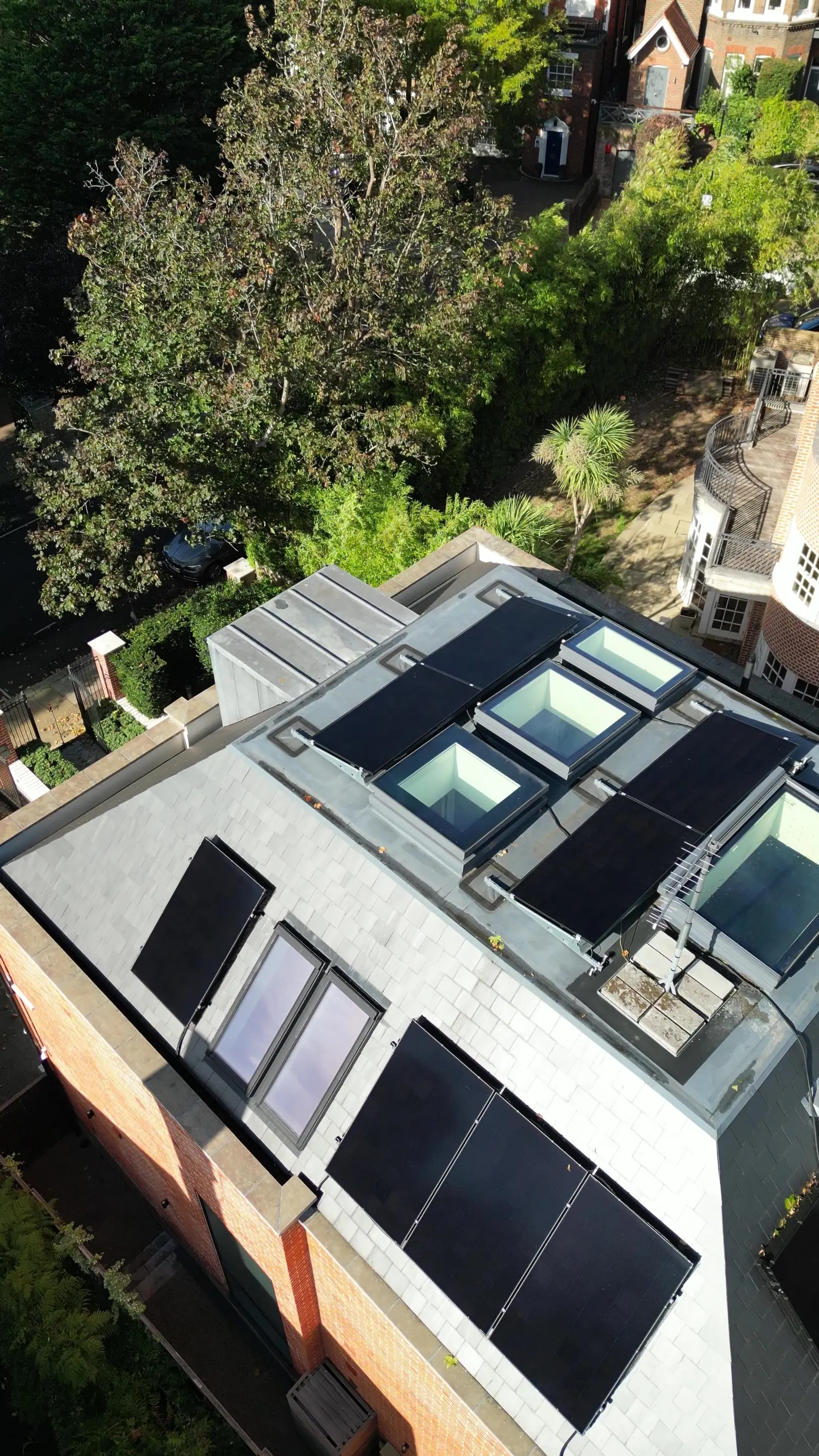 Solar panels and roof lights on the flat roof of a London house, seen from a drone